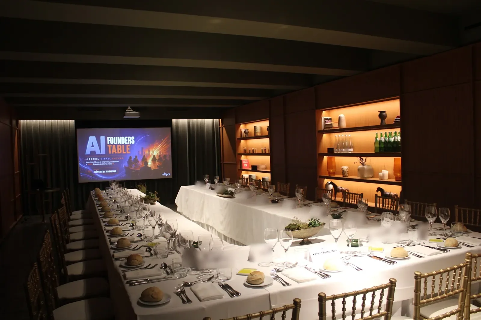 The AI Founders Table room with the table set for about twenty people and the screen at the back